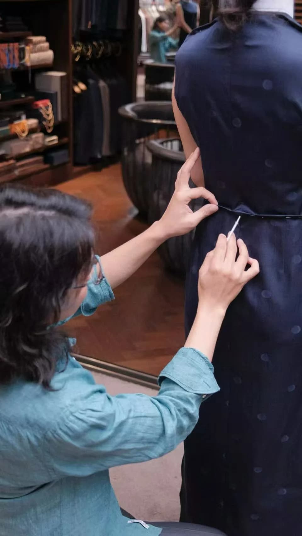 量体师调整藏蓝色无袖礼服腰部的无脸试衣画面